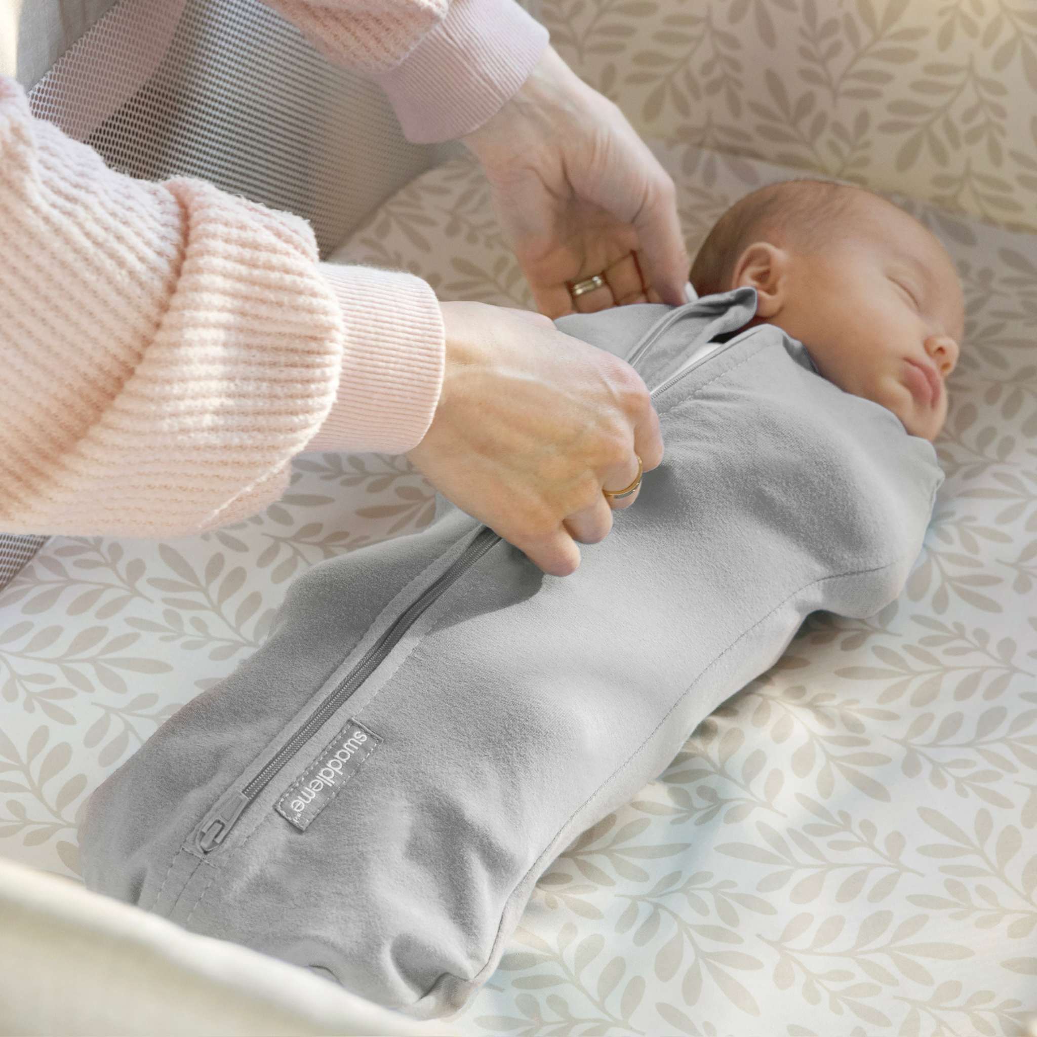 Newborn baby peacefully sleeping in a gray Ingenuity Velboa Pod swaddle with zipper closure for secure comfort and easy diaper changes