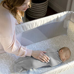 Newborn baby peacefully sleeping in Ingenuity Velboa Pod Clouds & Stars swaddle with caring mother nearby