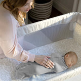 Newborn baby peacefully sleeping in Ingenuity Velboa Pod Clouds & Stars swaddle with caring mother nearby