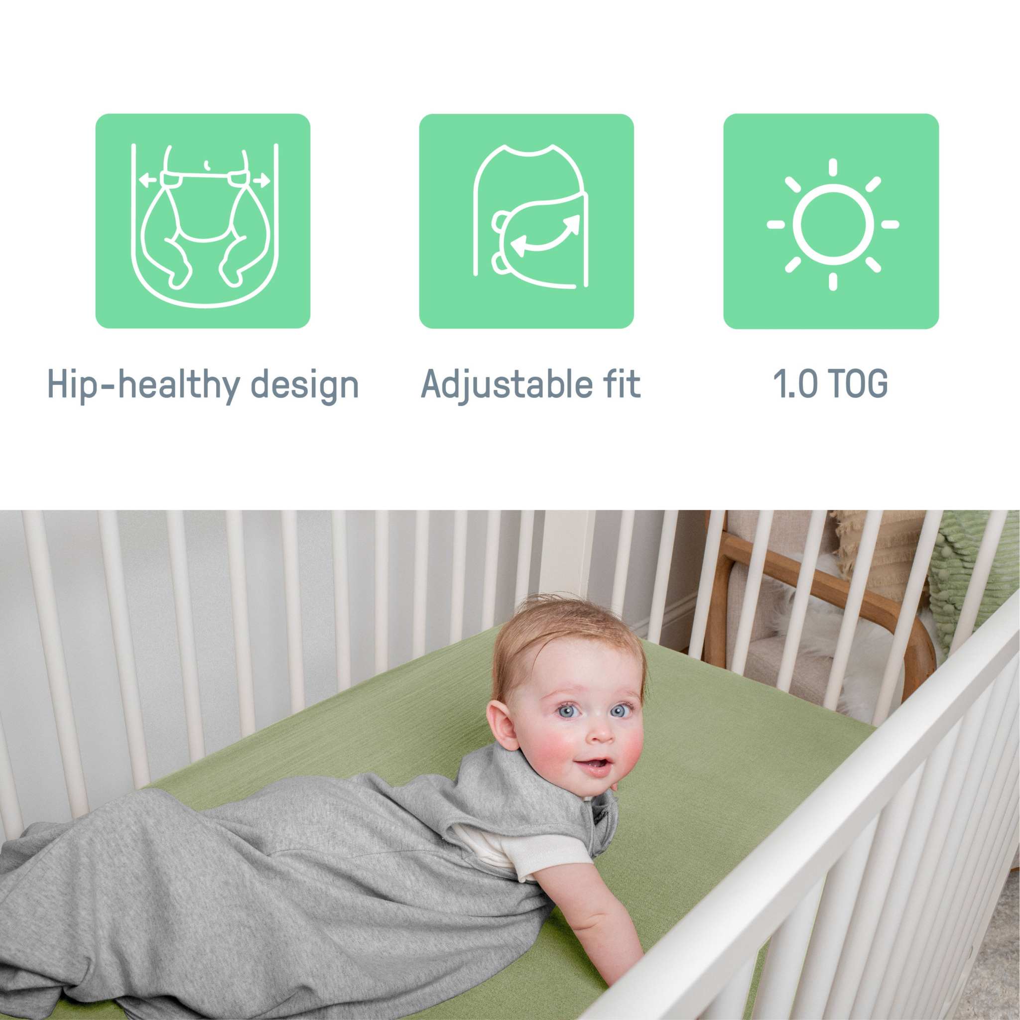 Baby in gray SwaddleMe by Ingenuity sleep sack lying in white crib with green mattress showing hip-healthy design, adjustable fit, and 1.0 TOG features
