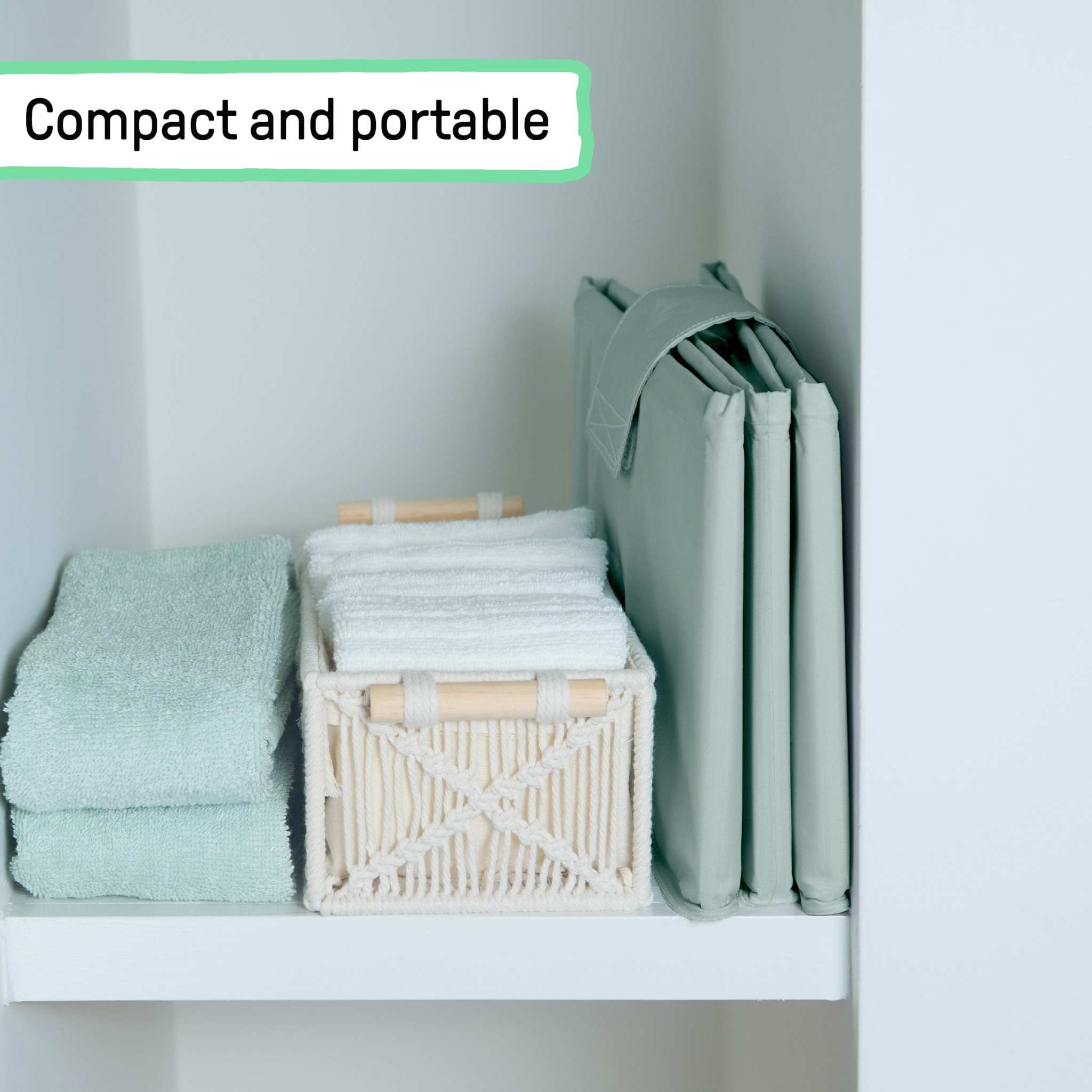 Folded compact Ingenuity Tuckaway Travel Tub stored neatly on a shelf with towels and basket.