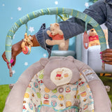 Winnie the Pooh baby bouncer with plush toys and colorful cushioned seat for infants.