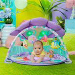 Mermaid Twinkle Trove Lights & Music Activity Gym with baby under purple seashell canopy, featuring colorful toys and tropical design.