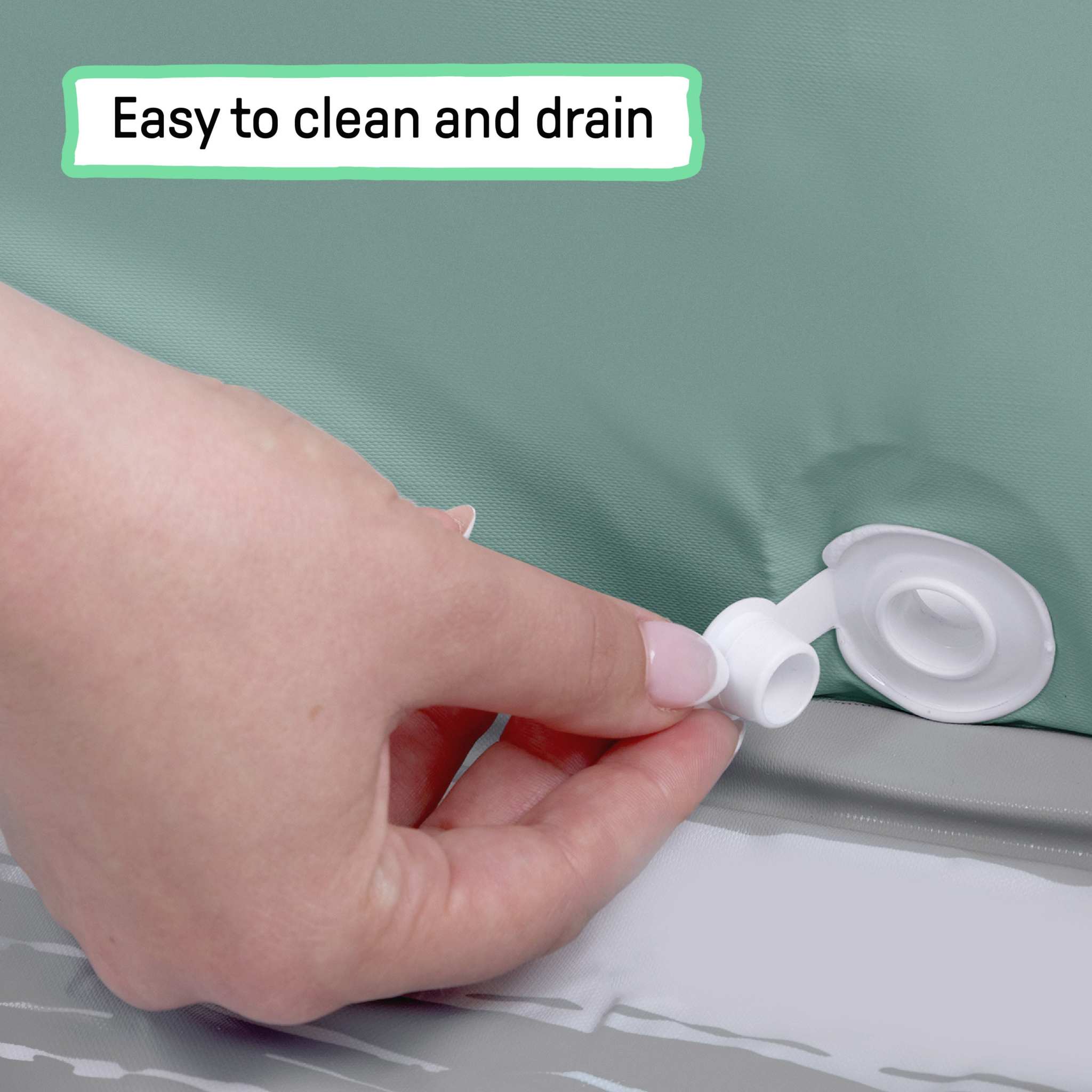 Close-up of hand opening the drain plug on the Ingenuity Tuckaway Travel Tub easy-to-clean waterproof travel tub for children.