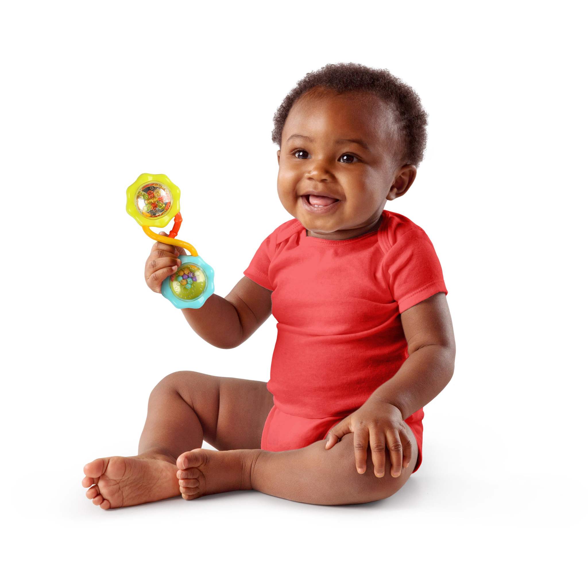 Baby holding Bright Starts Soothers & Shakers 7-piece gift set toy, smiling, wearing red onesie.