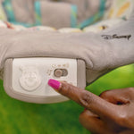Close-up of a finger pressing the music and volume control button on the Winnie the Pooh Baby Bouncer infant seat