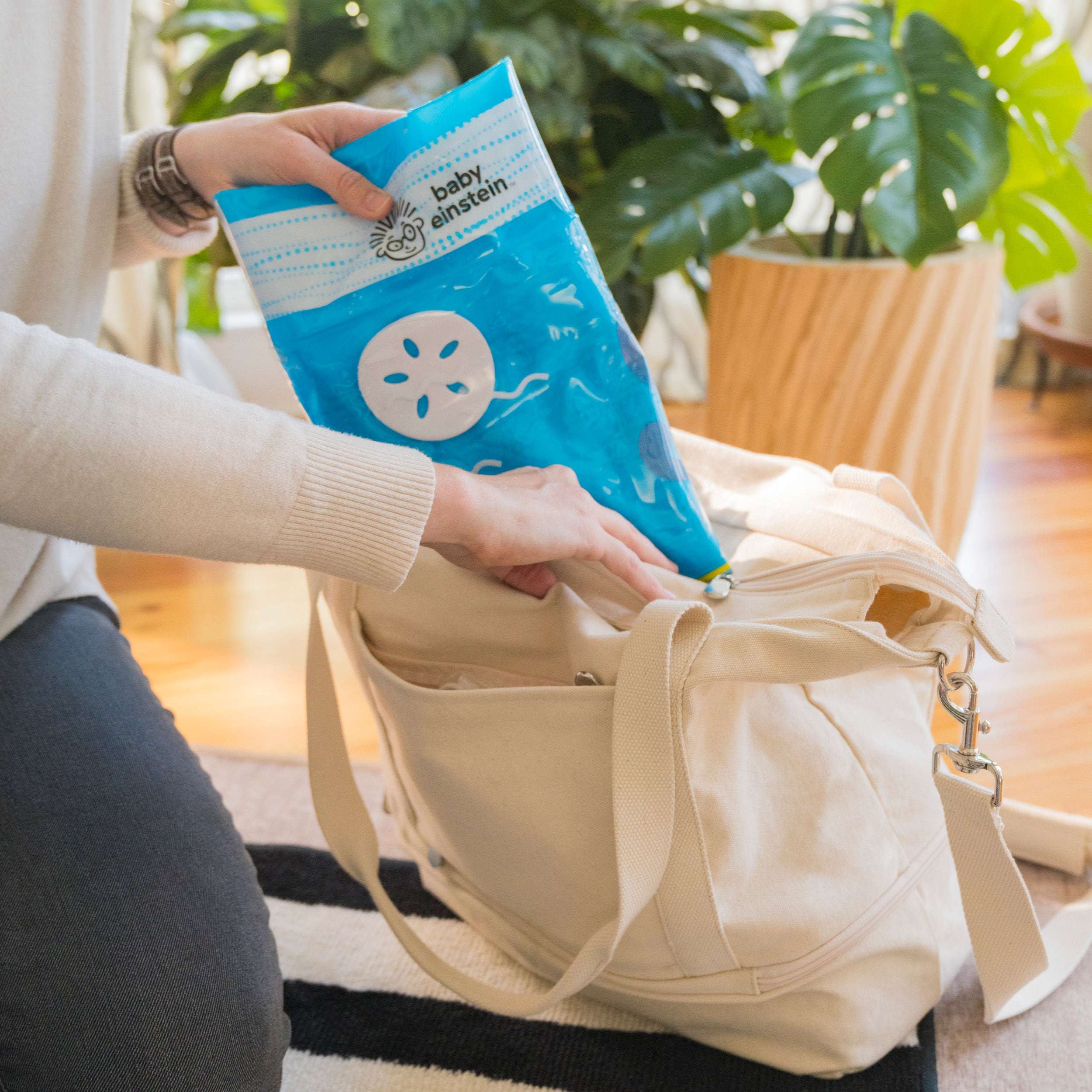 Opus’s Ocean of Discovery Tummy Time Water Mat folded and being placed into a bag for easy transport.