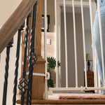White metal safety gate installed on a staircase, part of the Ingenuity Stairway+ 46W Series, designed for child and pet safety.
