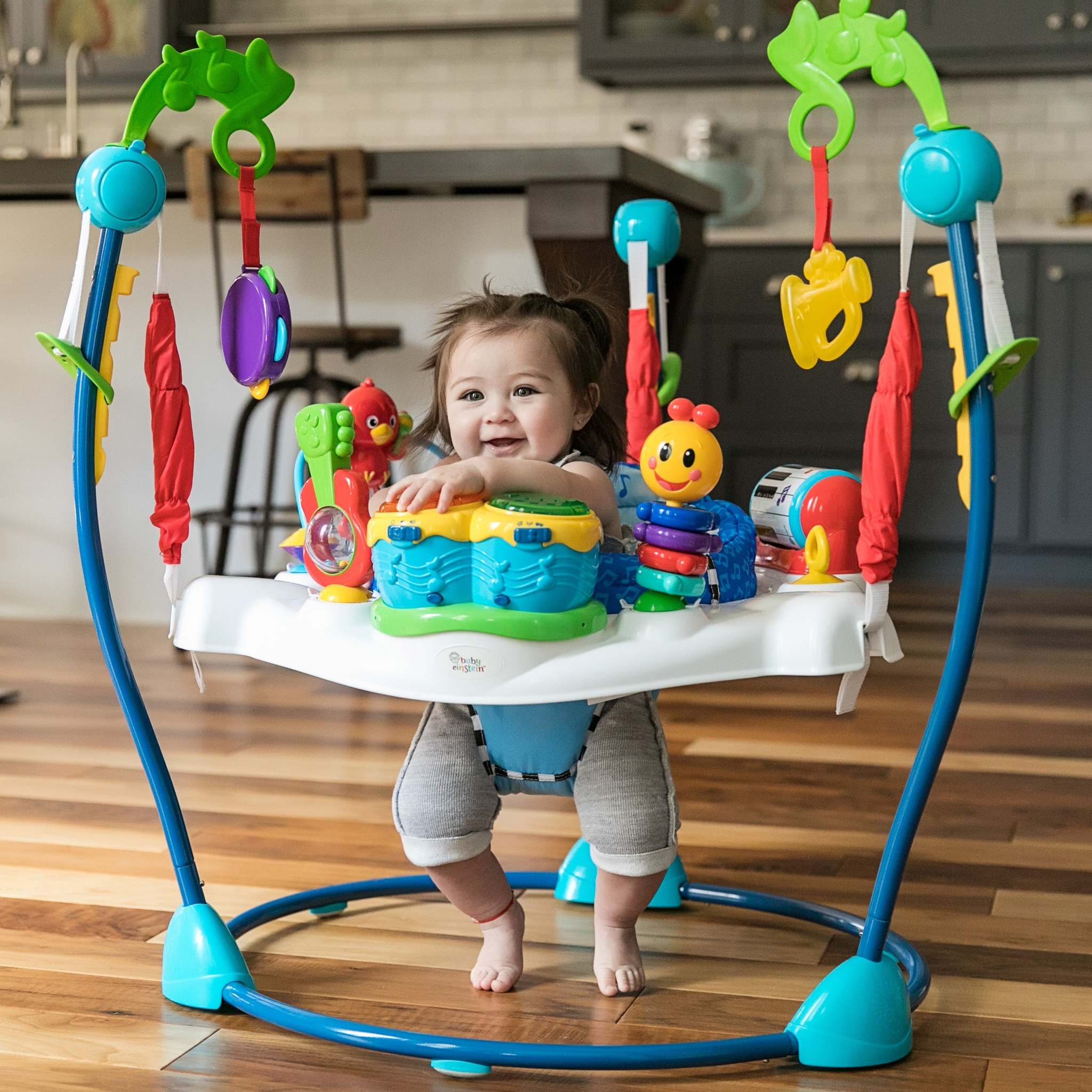 Baby playing in the Baby Einstein Neighborhood Symphony Activity Jumper with colorful musical toys and rotating seat.