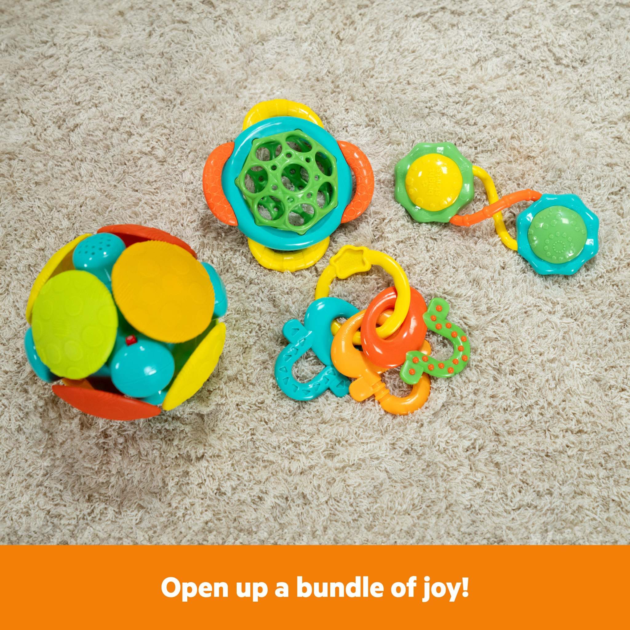 Bright Starts Catch Me Smile gift set with colorful baby toys including rattle, teether keys, and wobble ball on carpet