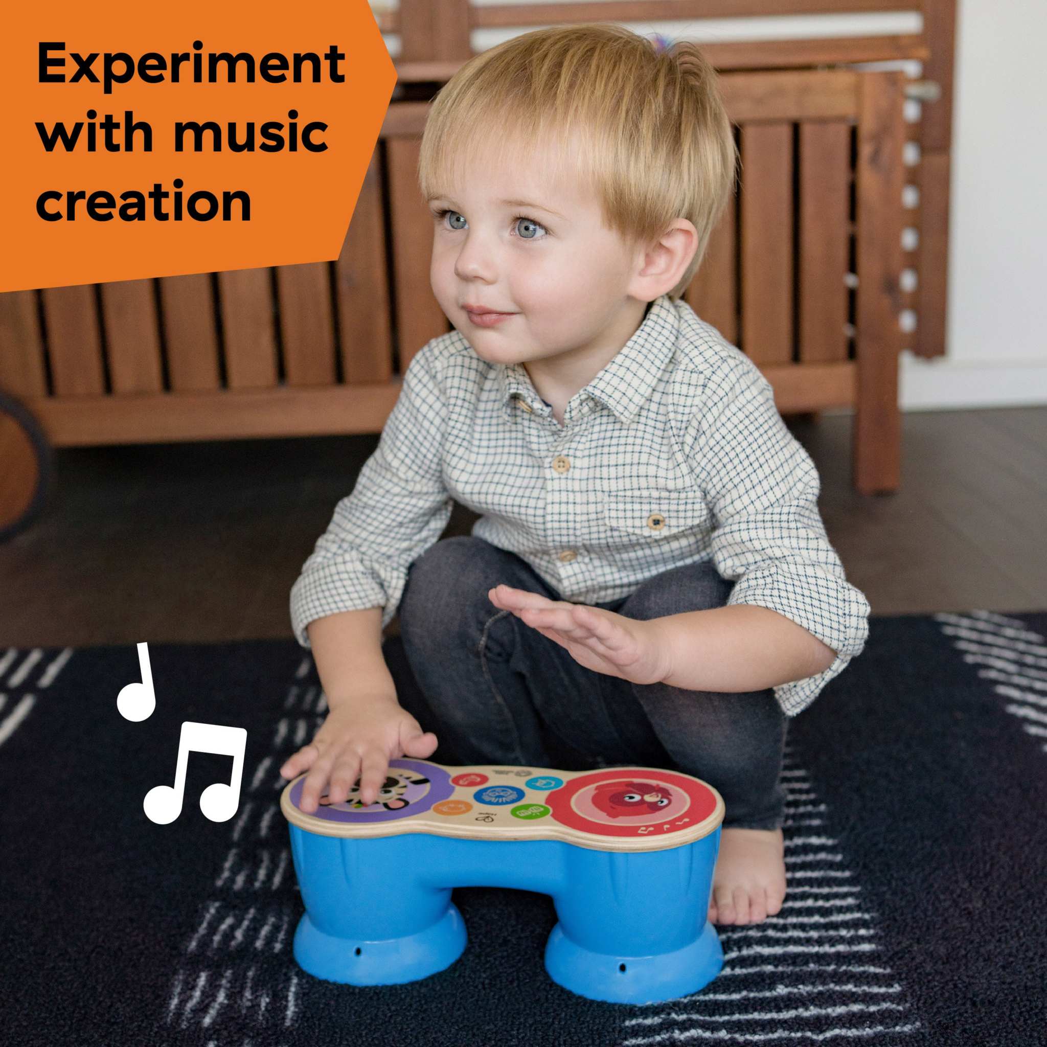 Baby playing with Baby Einstein First Tunes Drum and Shakers musical toy set, creating music on a blue toy drum with colorful buttons.