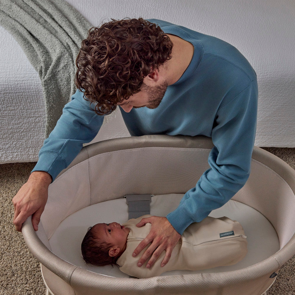 Man interacting with a baby in a bassinet