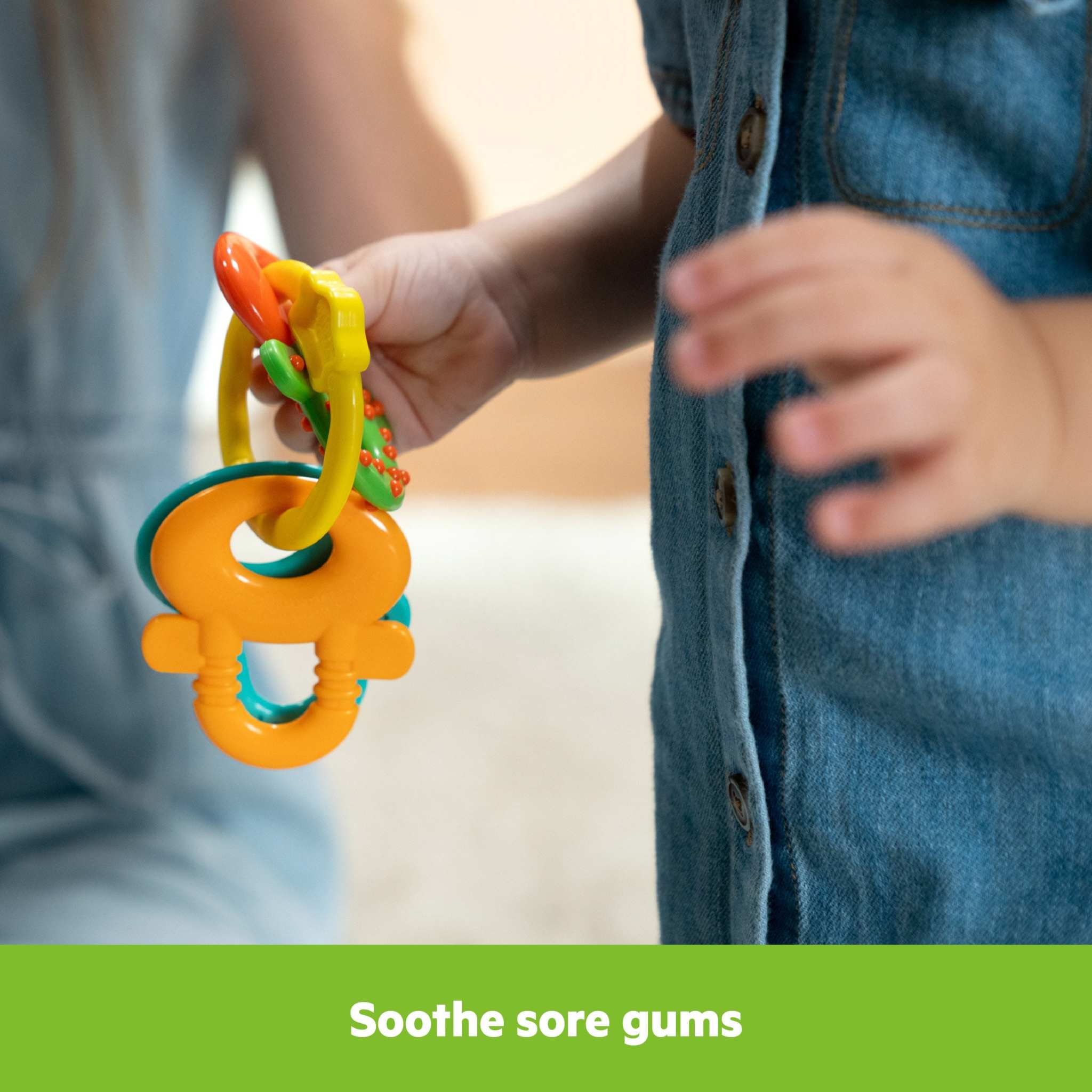 Baby holding Bright Starts Catch Me Smile gift set teething keys for soothing gums