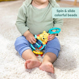 baby holding Disney Baby Winnie the Pooh sensory toy with colorful beads on carpet